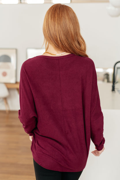 Person wearing a burgundy sweater in an indoor setting