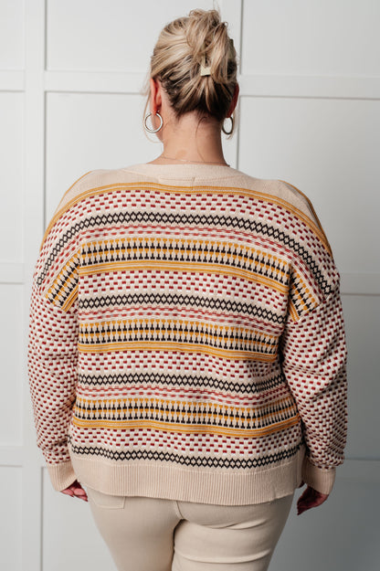 Person wearing a patterned sweater against a white tiled wall