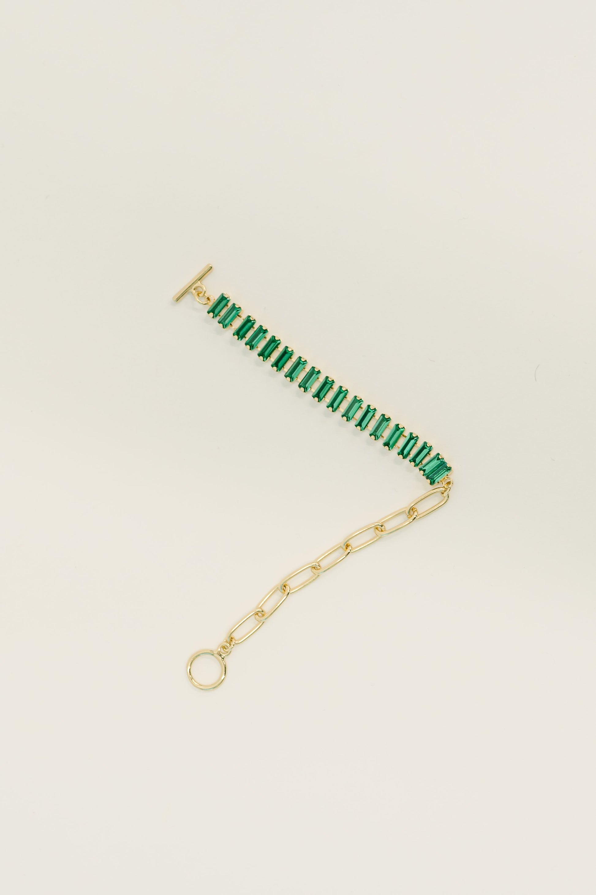 Gold bracelet with green beads on a beige background
