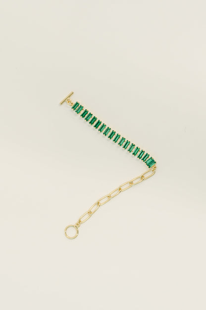 Gold bracelet with green beads on a beige background