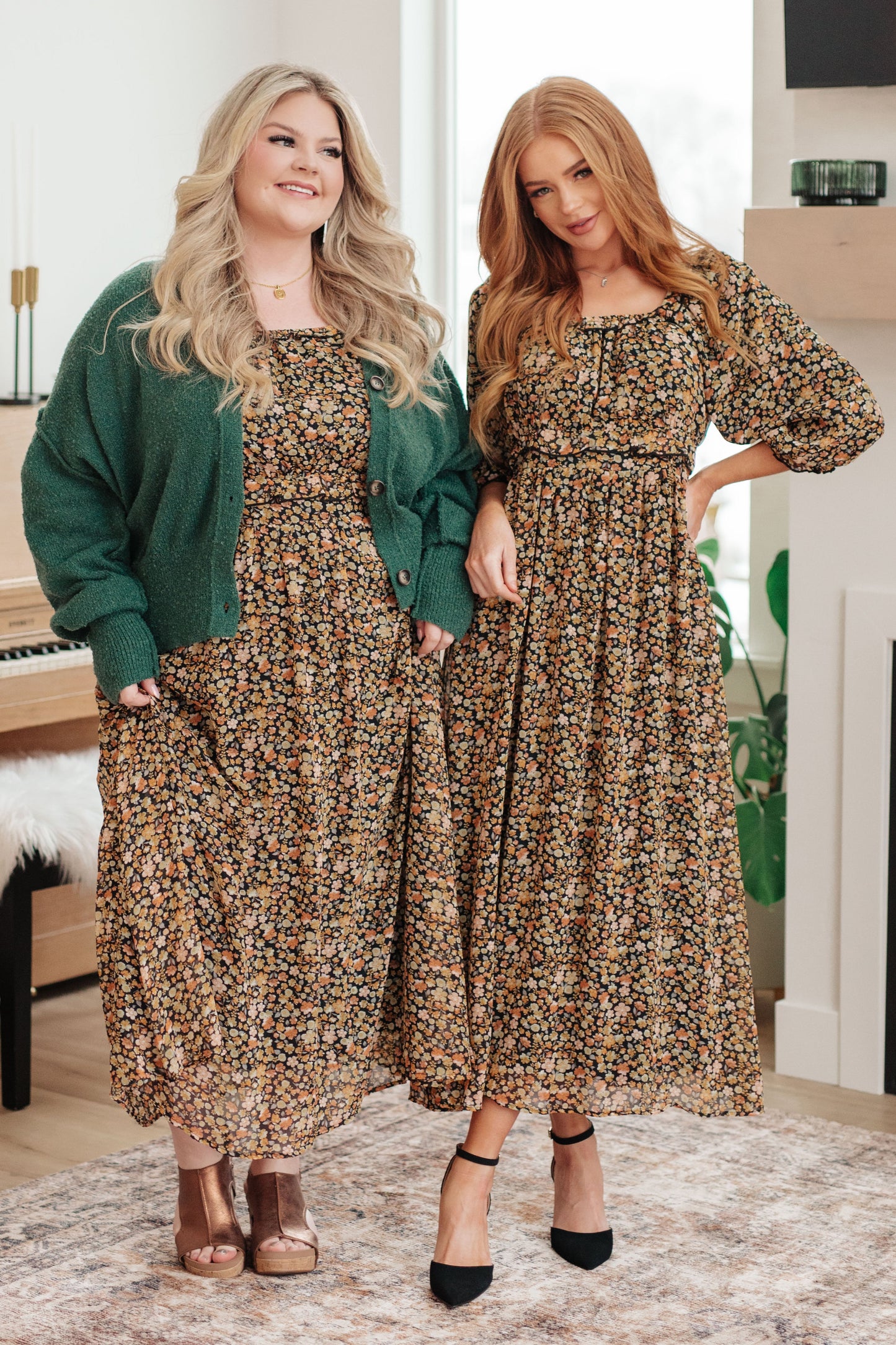 Two women wearing floral dresses in a room with a piano and decor.