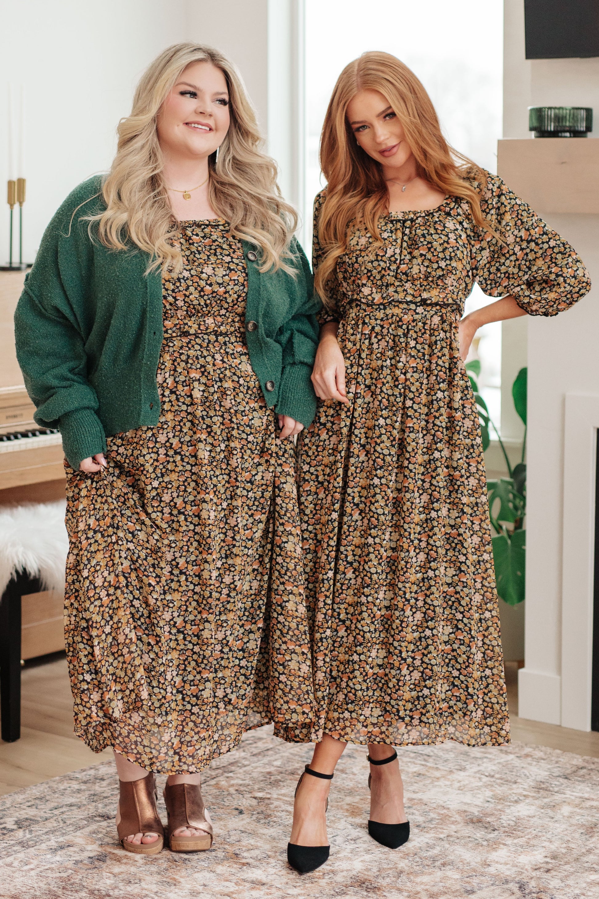 Two women wearing floral dresses in a room with a piano and decor.