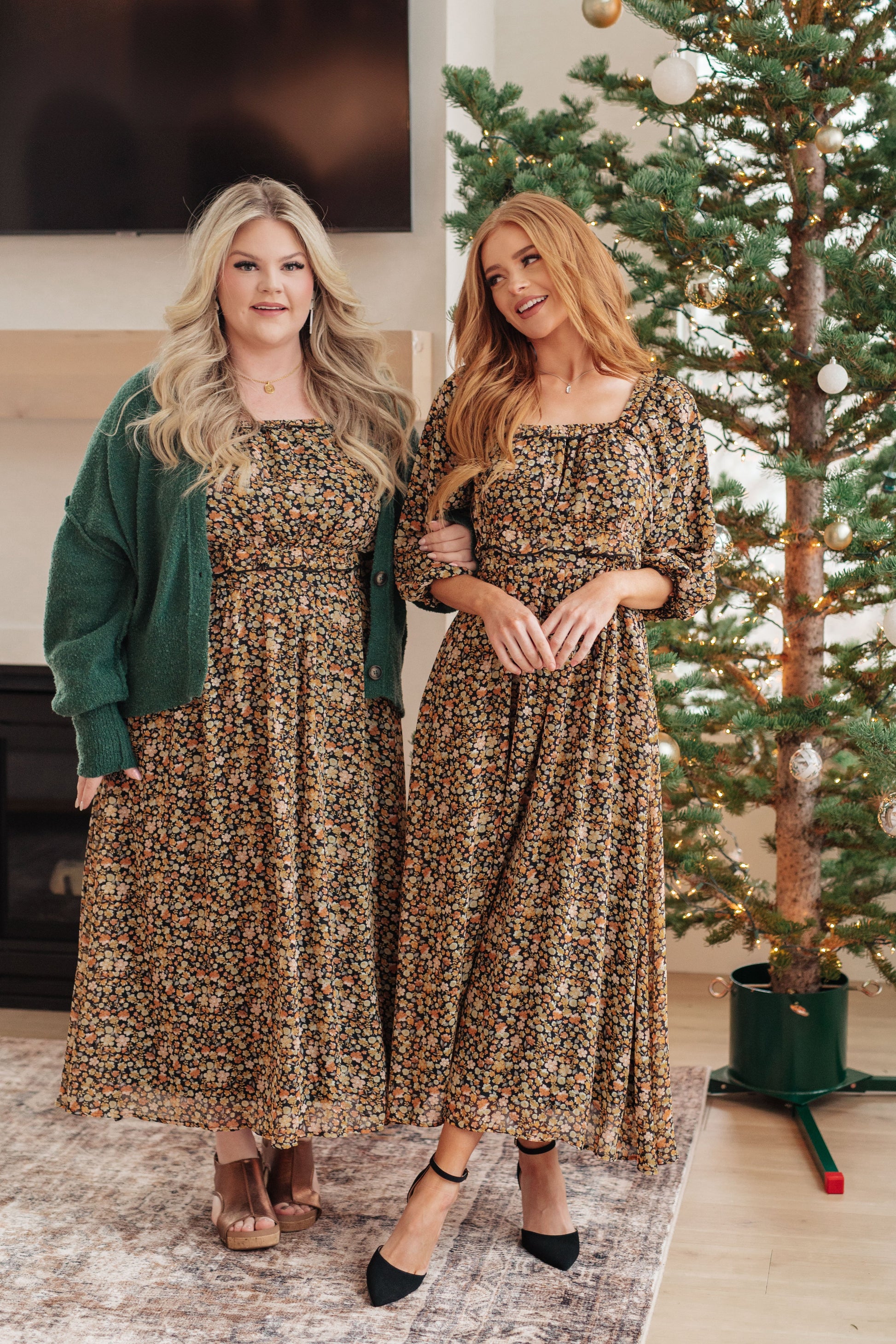Two women wearing matching leopard print dresses standing in front of a Christmas tree.