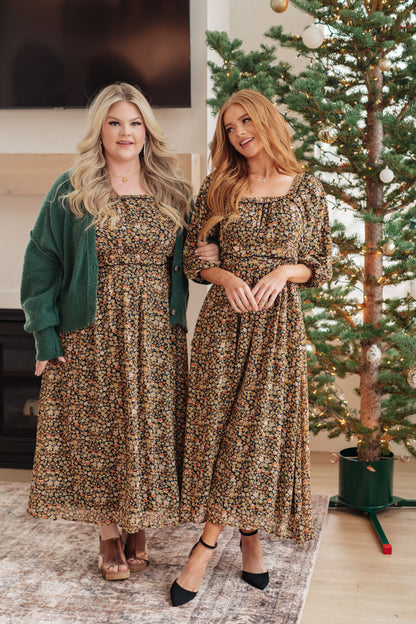Two women wearing matching leopard print dresses standing in front of a Christmas tree.