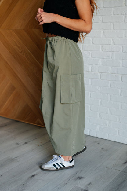 Person wearing olive green cargo pants with a white brick wall background