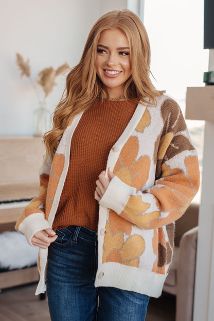 Woman wearing a patterned cardigan over a brown sweater in a home setting