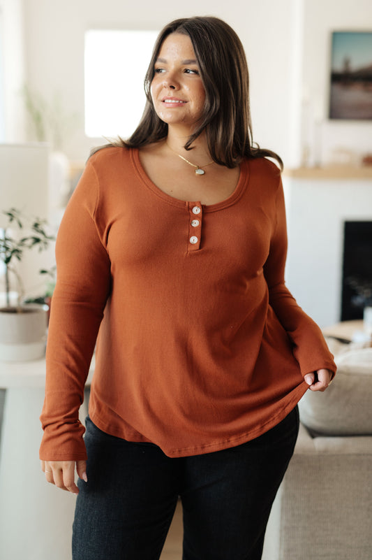Woman wearing a rust-colored long-sleeve shirt in a living room setting