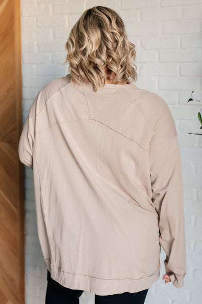 Person wearing a beige jacket standing against a white brick wall.
