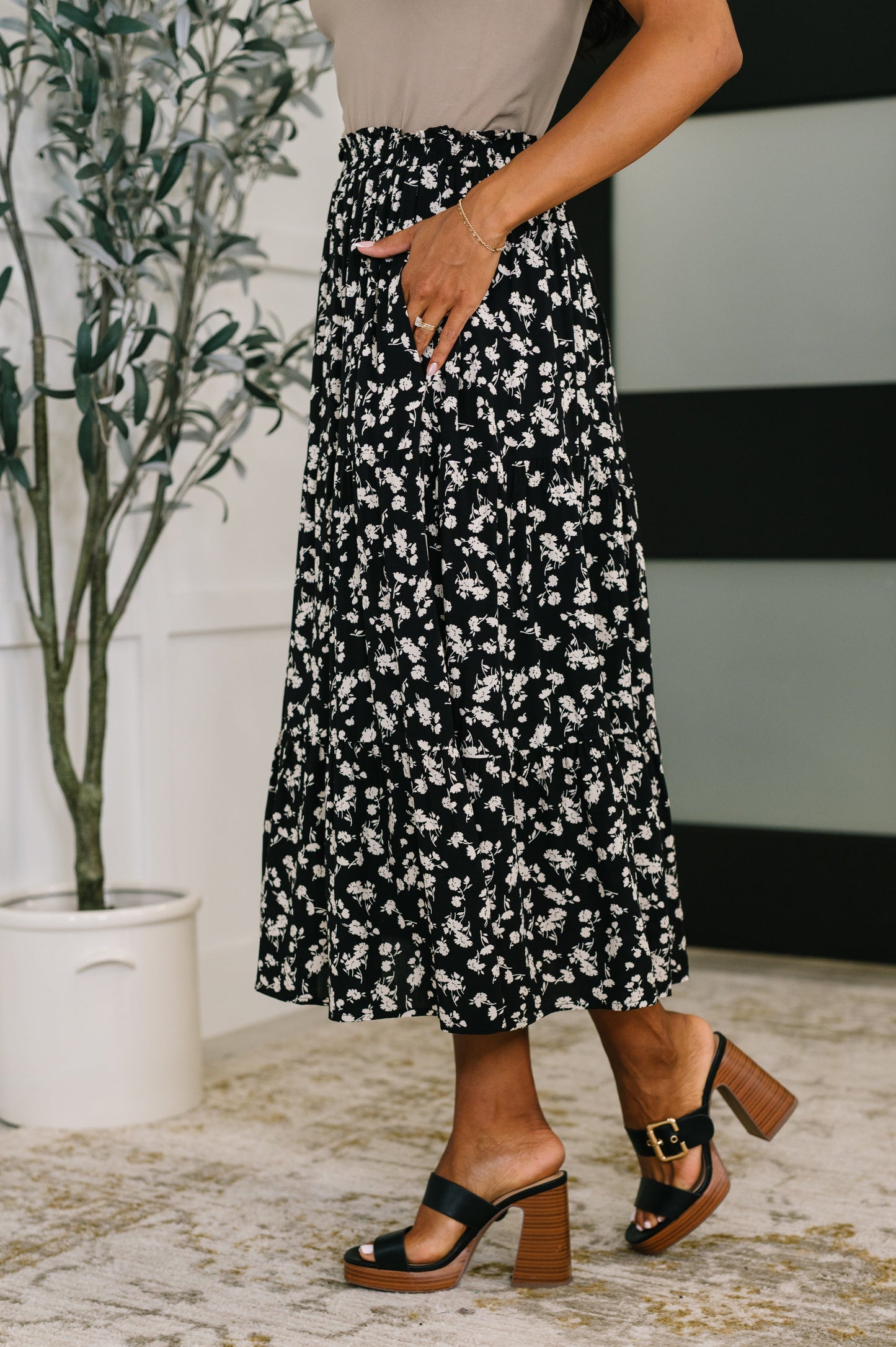 Person wearing a black and white floral skirt with a neutral background