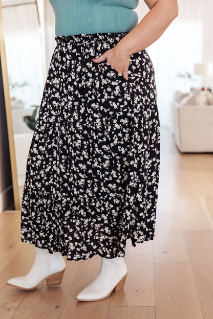 Person wearing a black floral skirt with white boots indoors