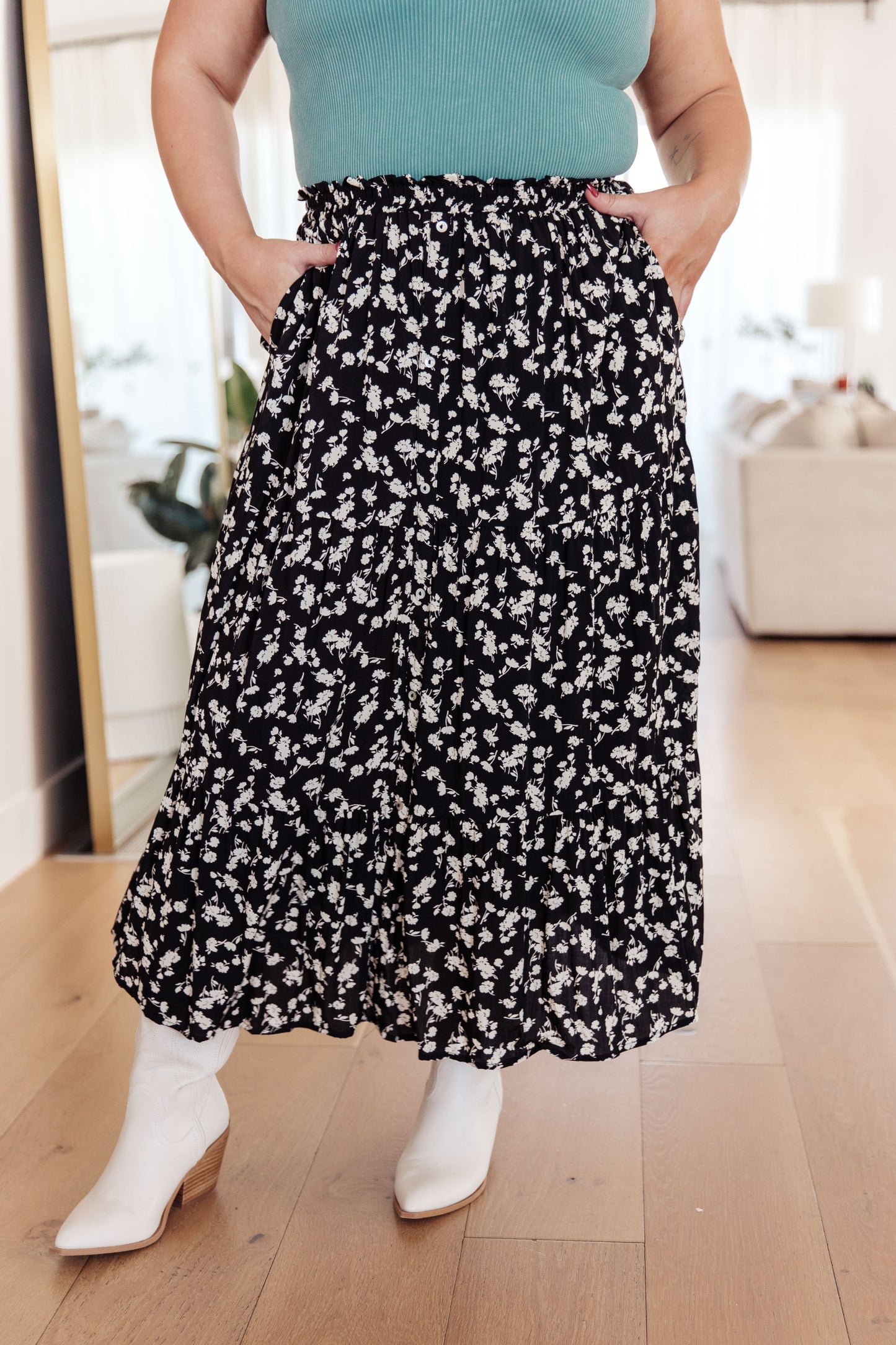 Person wearing a black floral skirt with white shoes indoors