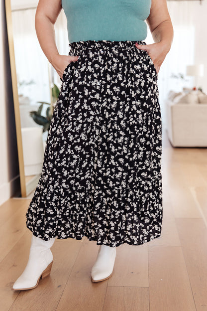 Person wearing a black floral skirt with white shoes indoors