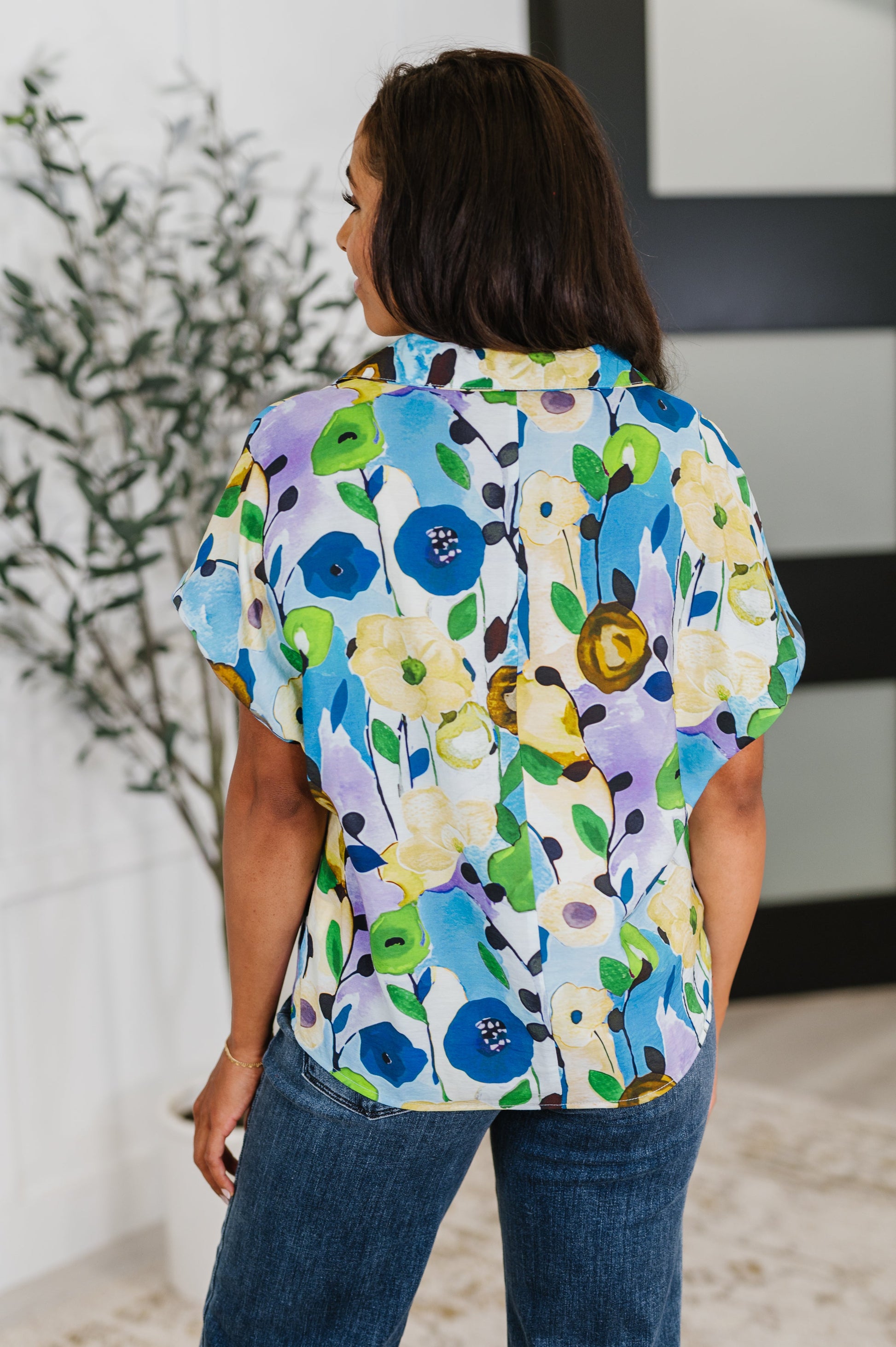 Person wearing a colorful floral blouse with a blurred indoor background