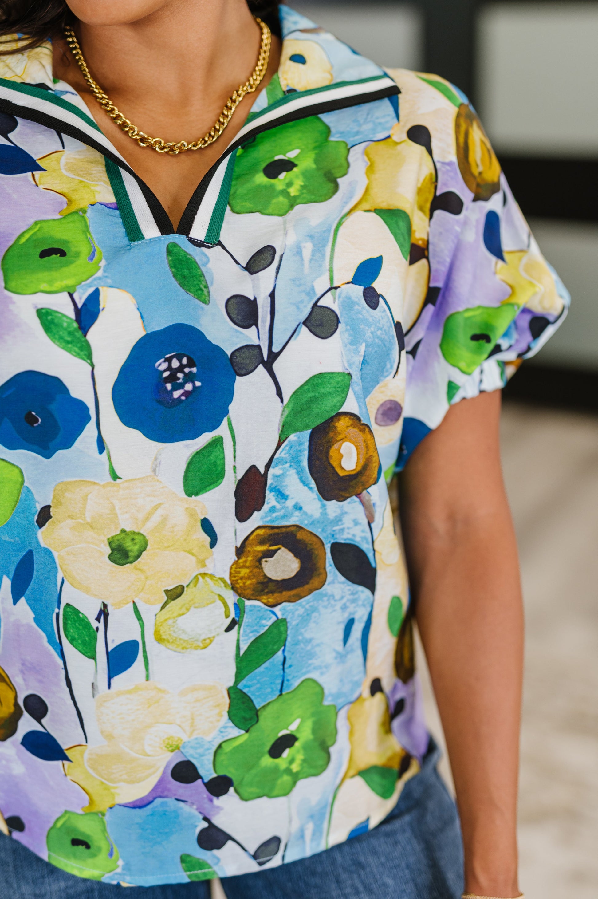 Colorful floral-patterned shirt worn by a person, with a blurred indoor background.