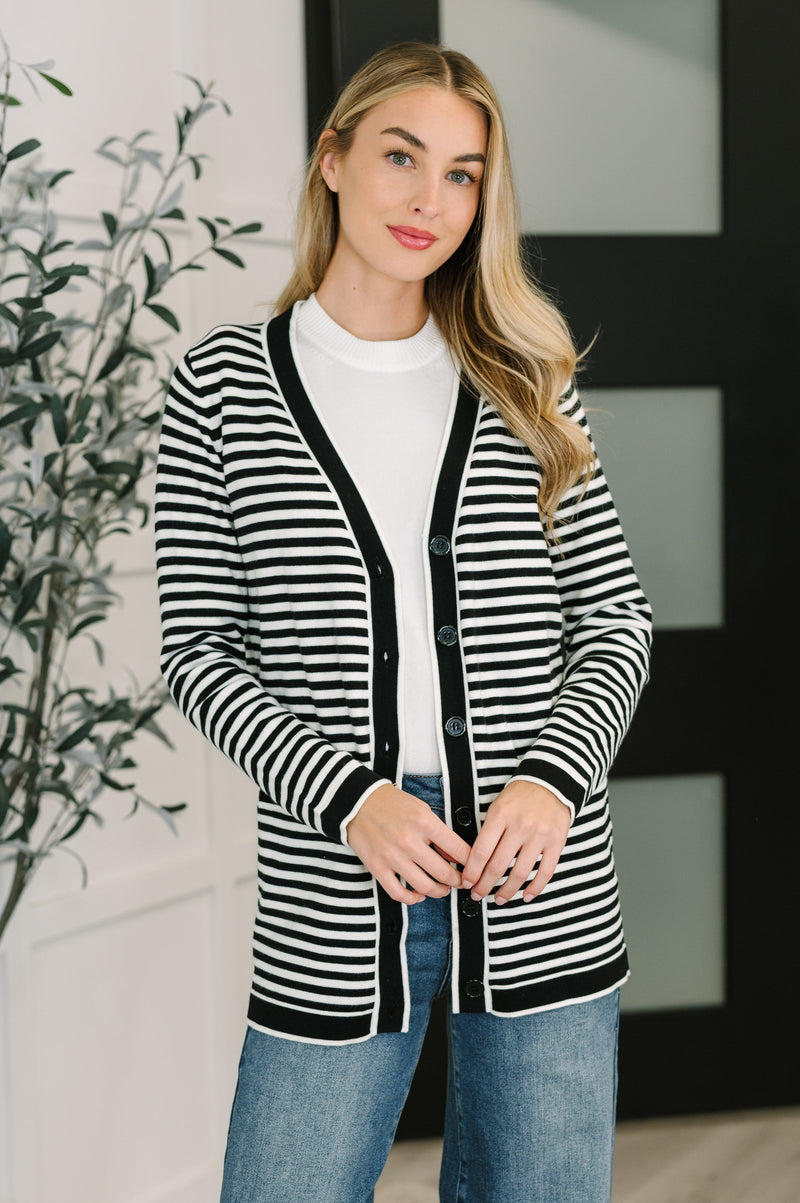 Woman wearing a black and white striped cardigan in an indoor setting