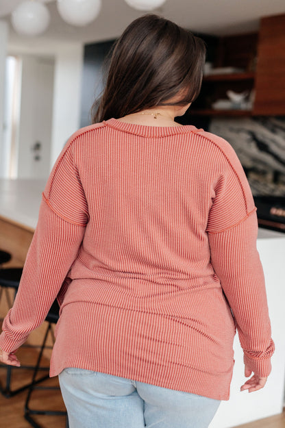 Person wearing a pink ribbed sweater in an indoor setting