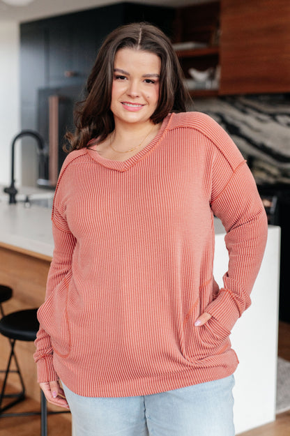 Woman wearing a pink ribbed sweater in a kitchen setting