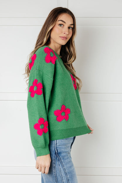 Woman wearing a green sweater with pink floral patterns against a white background