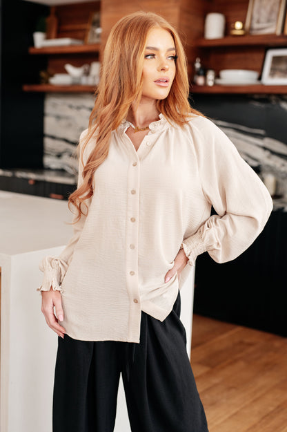 Woman wearing a beige blouse and black pants in an indoor setting