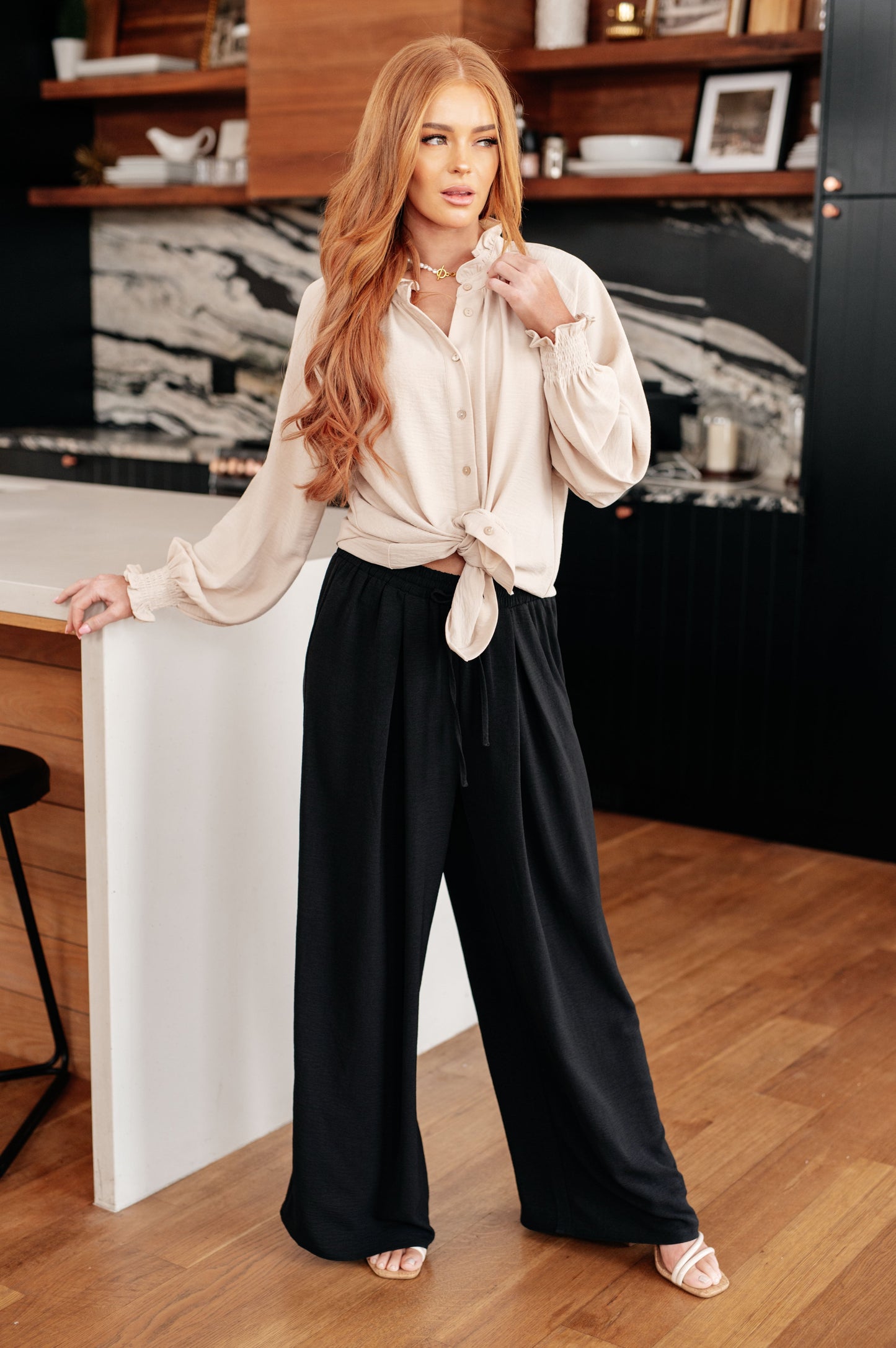 Woman in a stylish outfit standing in a modern kitchen.