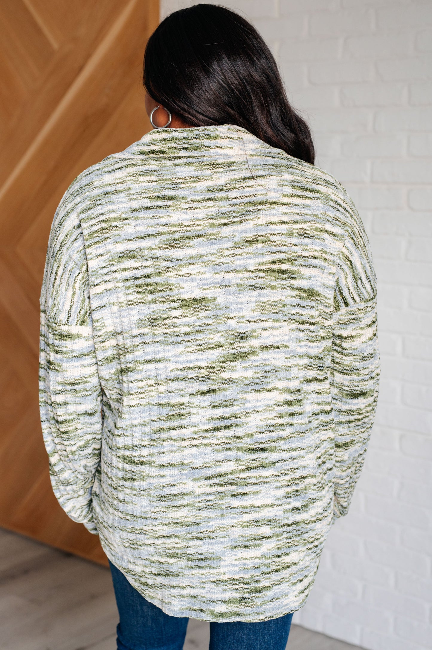 Person wearing a green and white patterned sweater with a neutral background