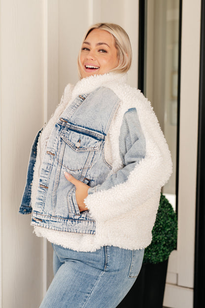 Woman wearing a denim jacket with white sherpa lining, standing indoors.