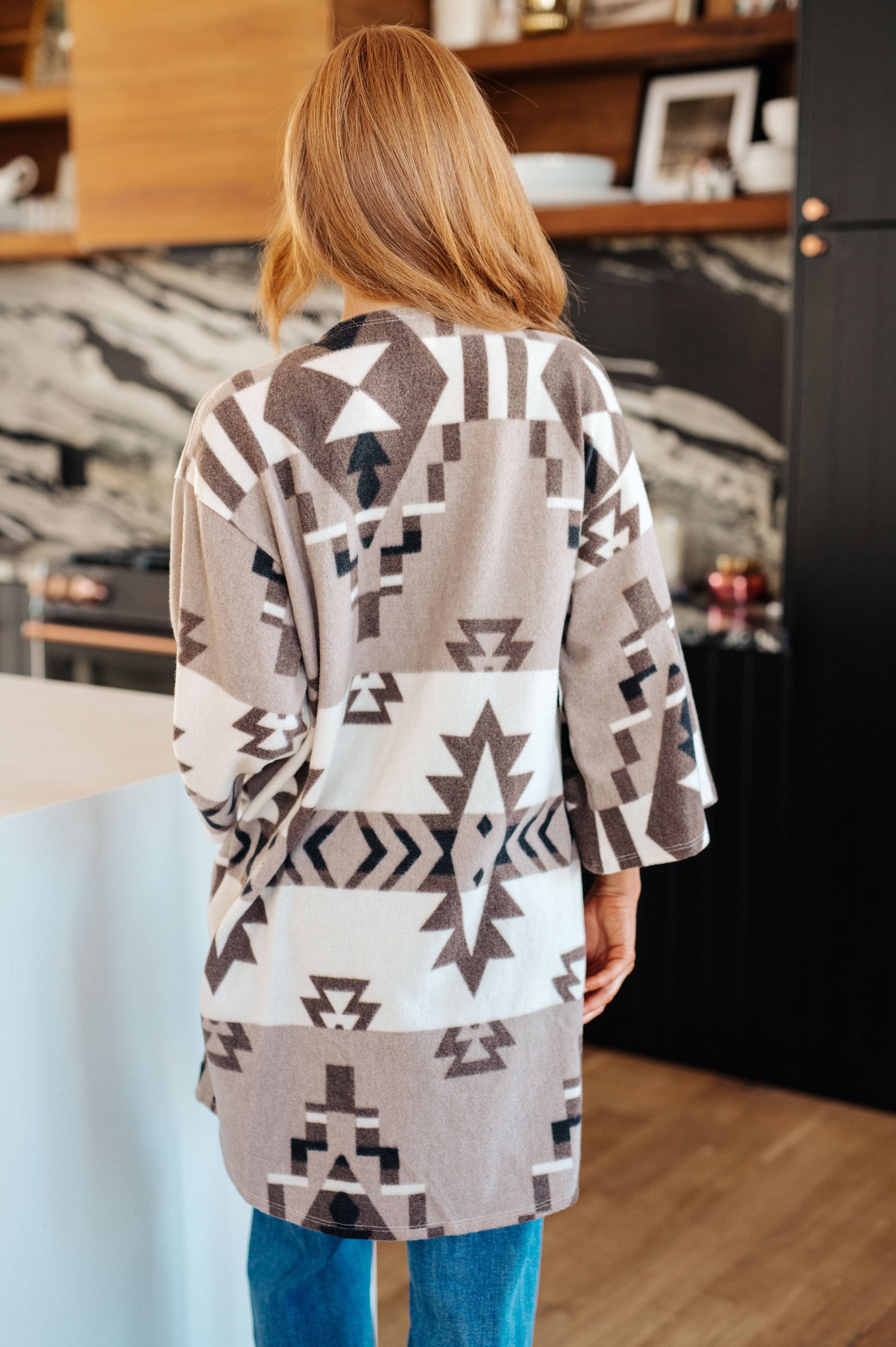 Person wearing a patterned cardigan in a kitchen setting