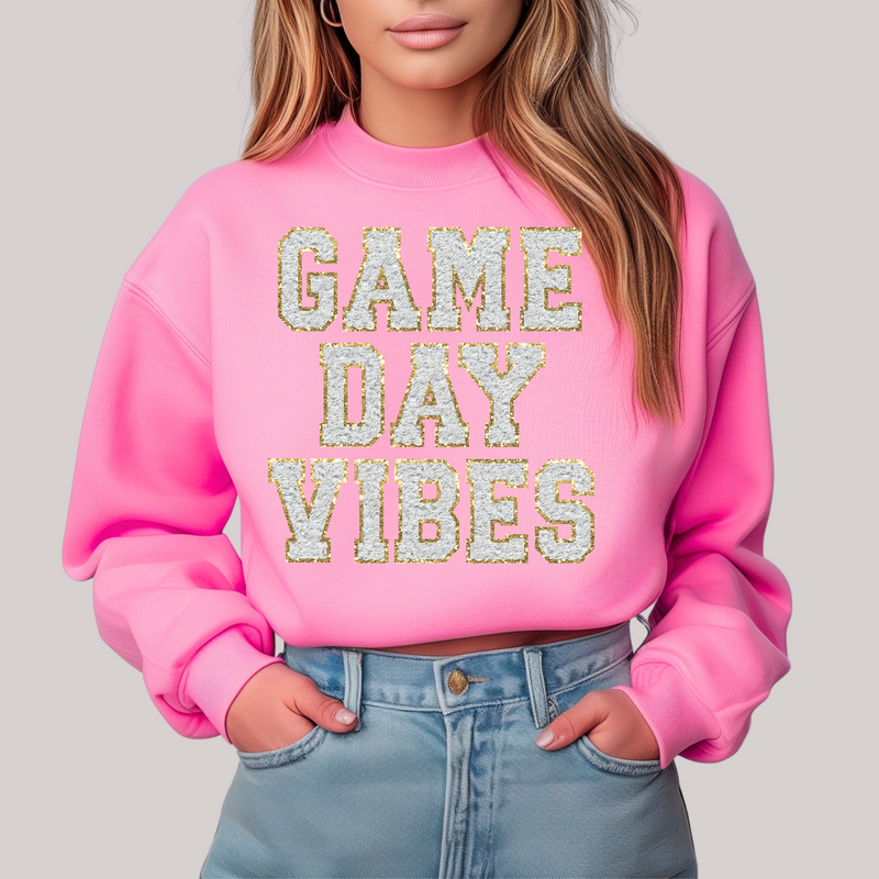 Person wearing a pink sweatshirt with 'GAME DAY VIBES' text on a plain background