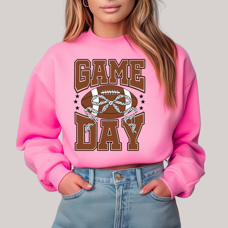Person wearing a pink sweatshirt with 'Game Day' and football graphic on a plain background