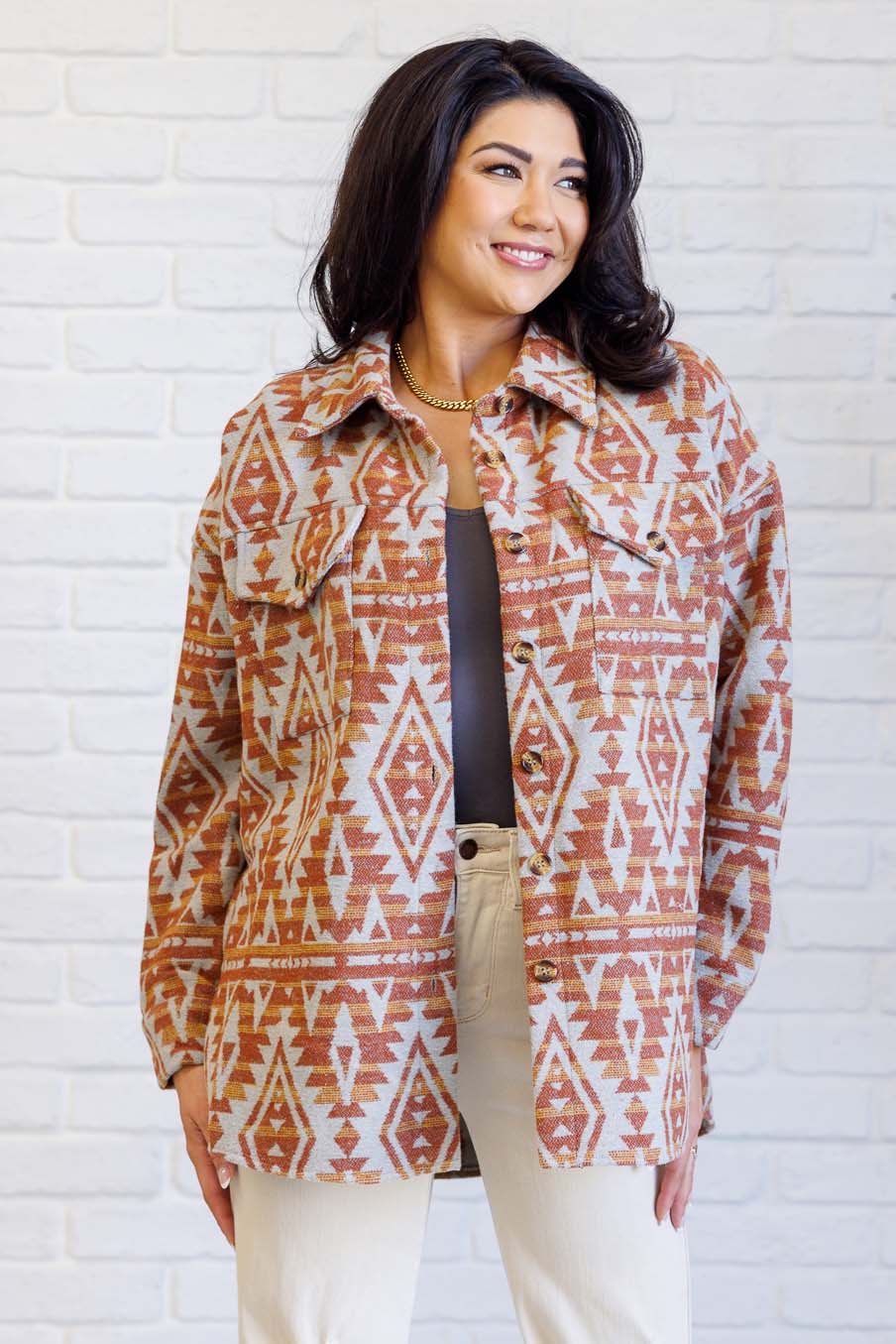 Woman wearing a patterned jacket in front of a white brick wall