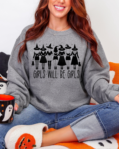 Person wearing a gray sweatshirt with 'Girls Will Be Girls' text, sitting on an orange and white blanket.