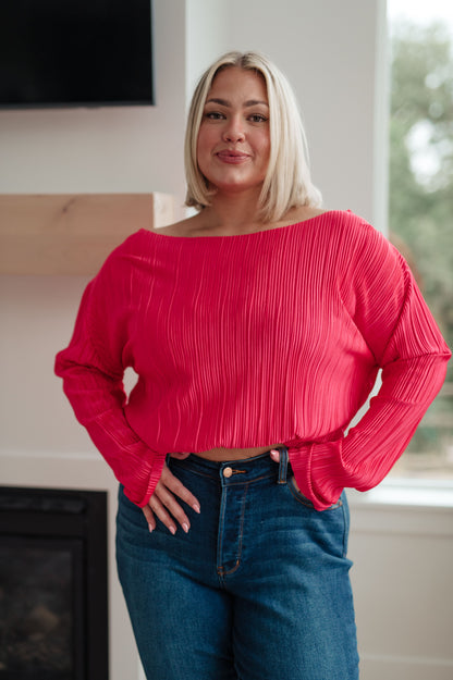 Woman wearing a red blouse and blue jeans indoors.