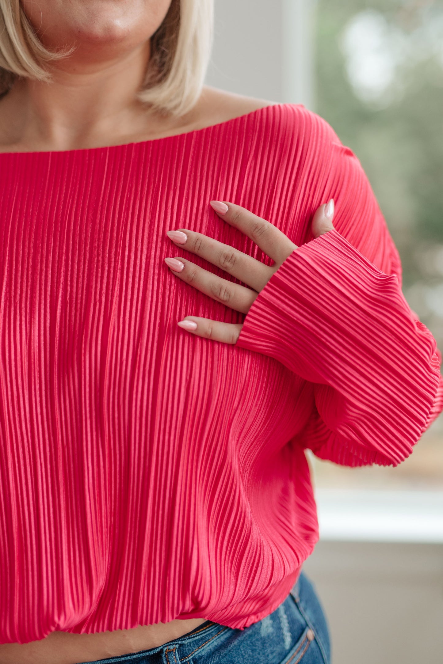 Person wearing a pink ribbed sweater with blurred background