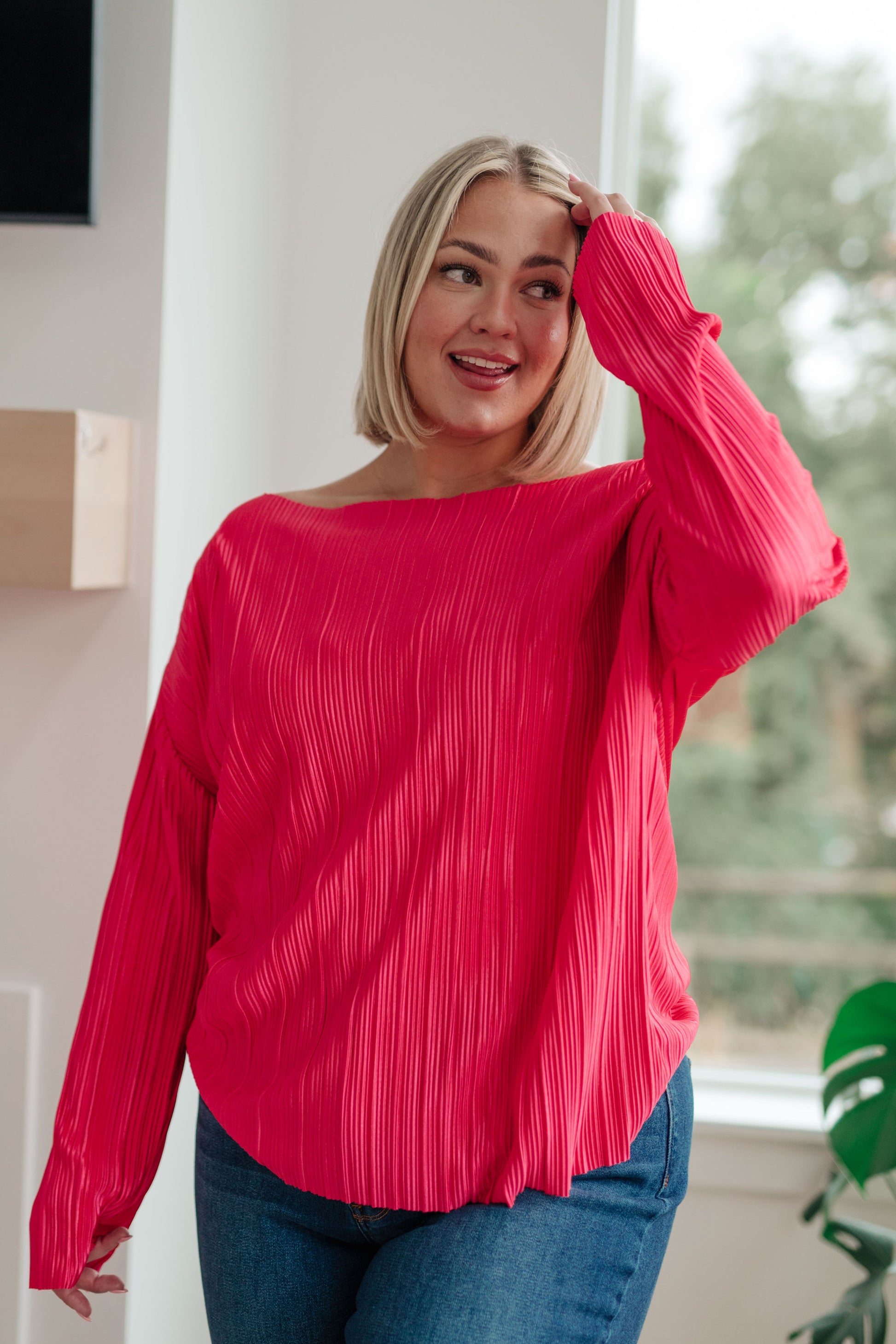 Woman wearing a bright pink blouse indoors with a blurred background