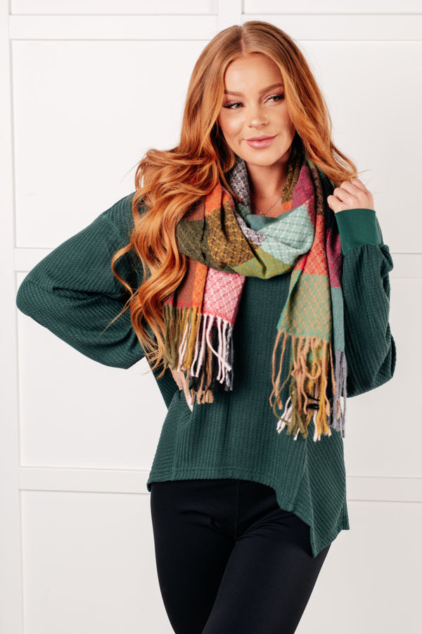 Woman wearing a green sweater and colorful scarf against a white background