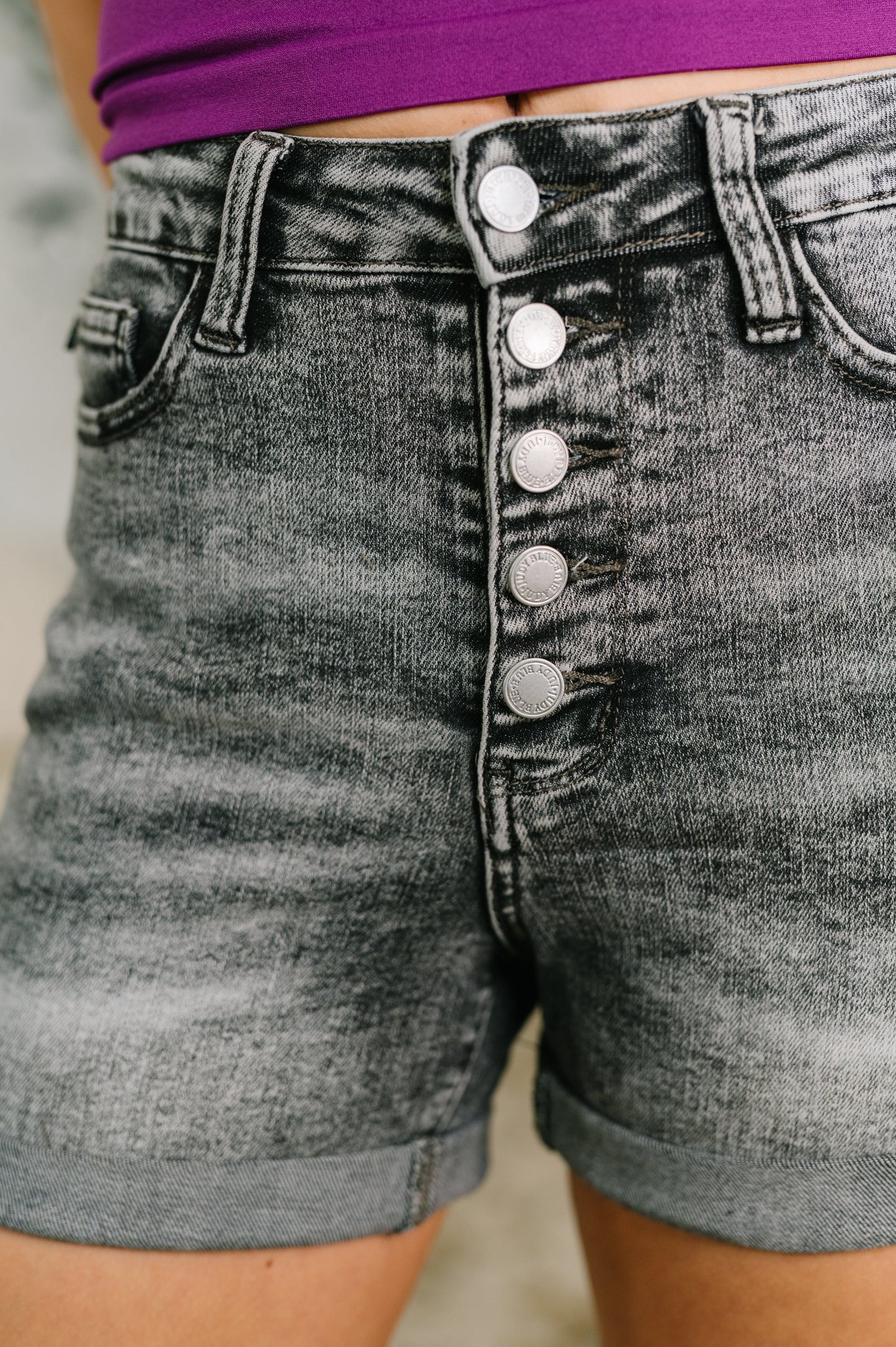 Gray denim shorts with button details on a blurred background