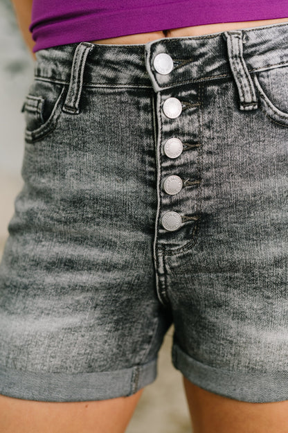 Gray denim shorts with button details on a blurred background