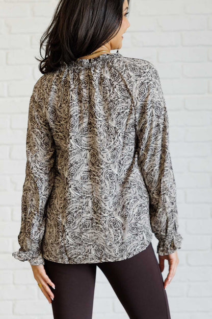 Woman wearing a patterned blouse against a white brick wall