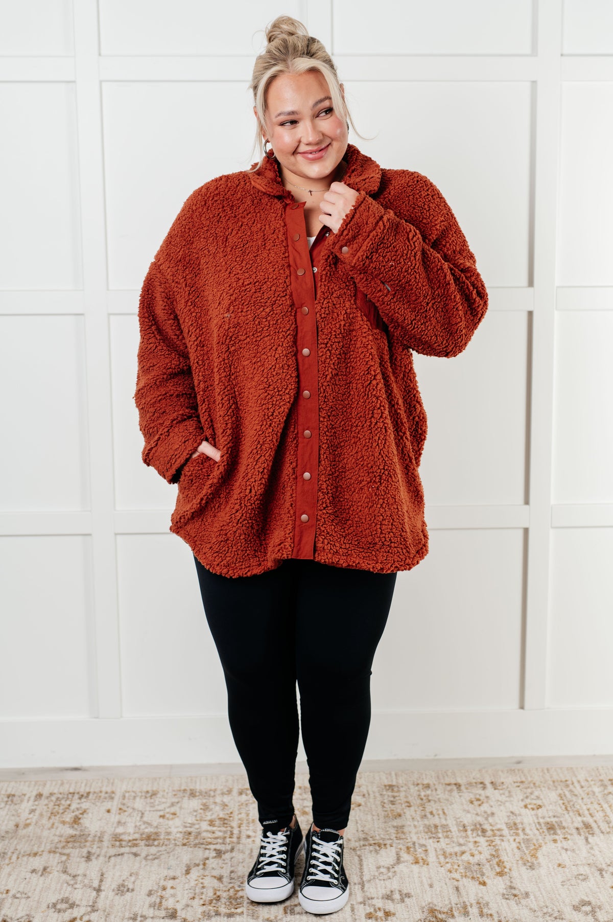 Person wearing a red sherpa jacket with a white wall background