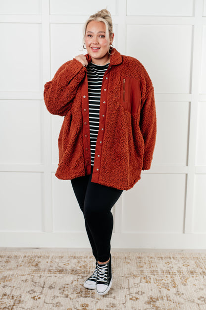 Person wearing a red jacket over a striped shirt with black pants and sneakers on a white background