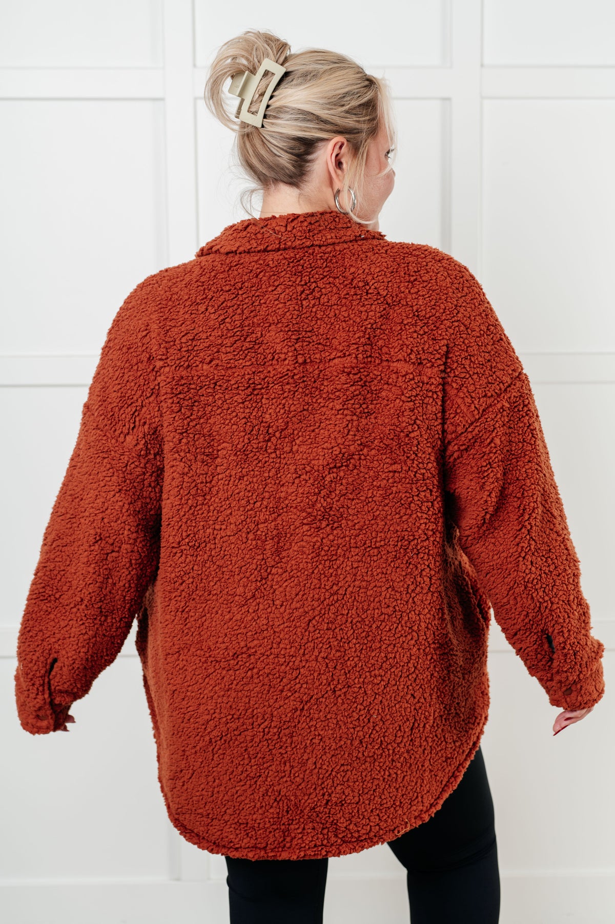Person wearing a rust-colored sherpa jacket against a white background