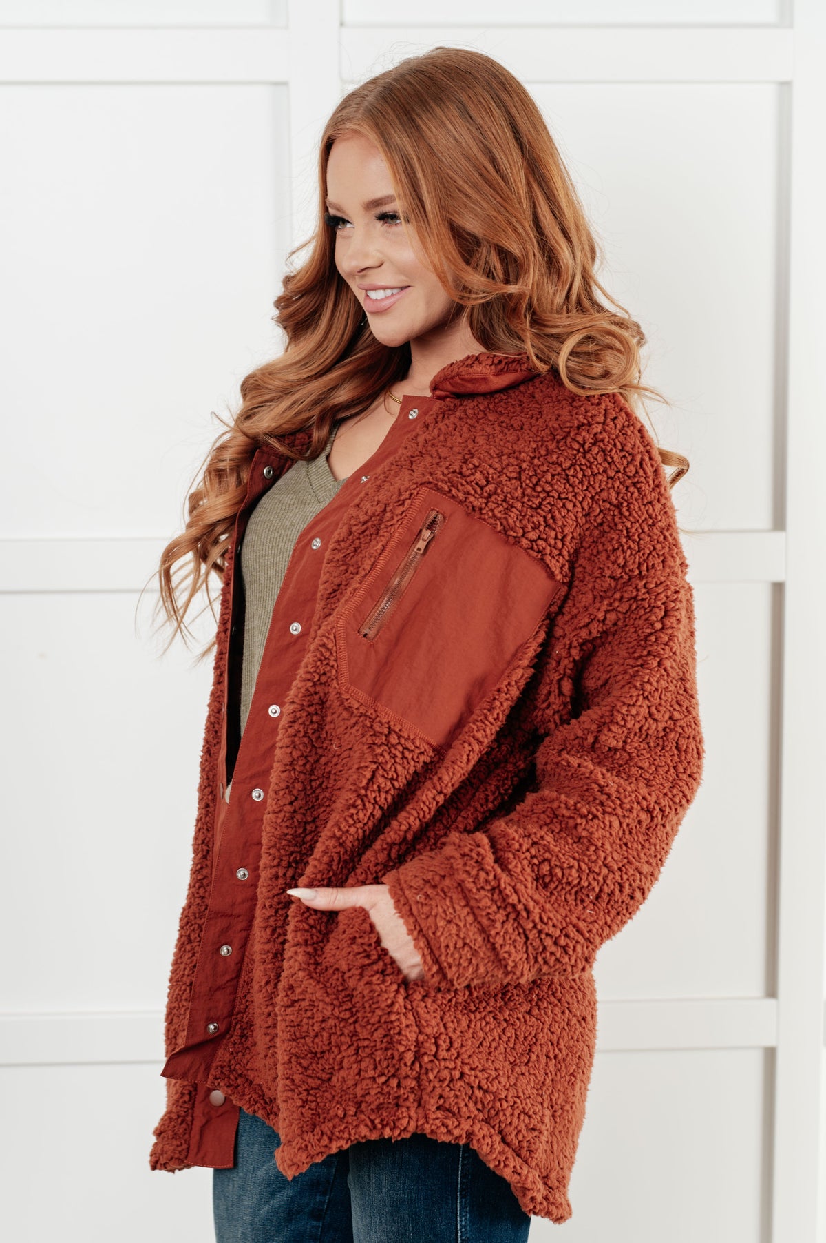 Woman wearing a brown sherpa jacket against a white background