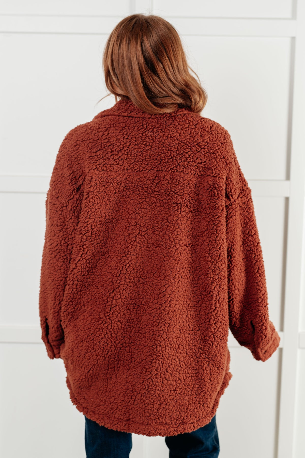 Person wearing a brown sherpa jacket against a white background