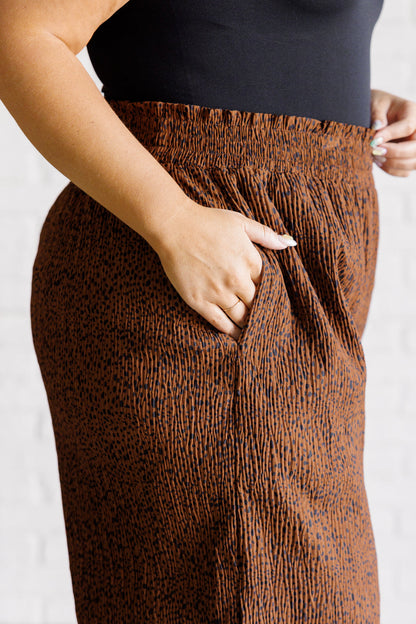 Brown patterned pants worn by a person on a white background