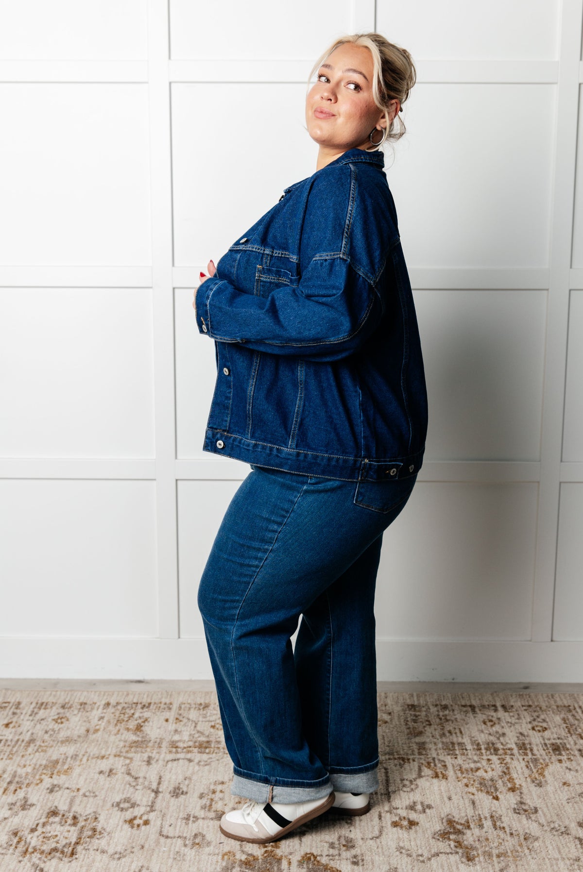 Person wearing a blue denim outfit standing against a white wall.