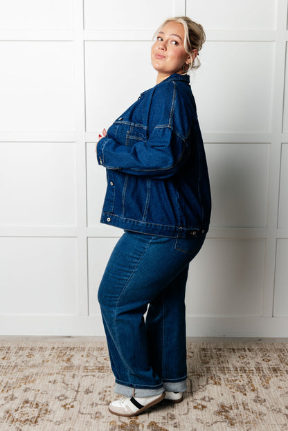 Person wearing a blue denim outfit standing against a white wall.