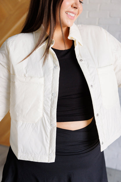 Woman wearing a white quilted jacket over a black top and pants.