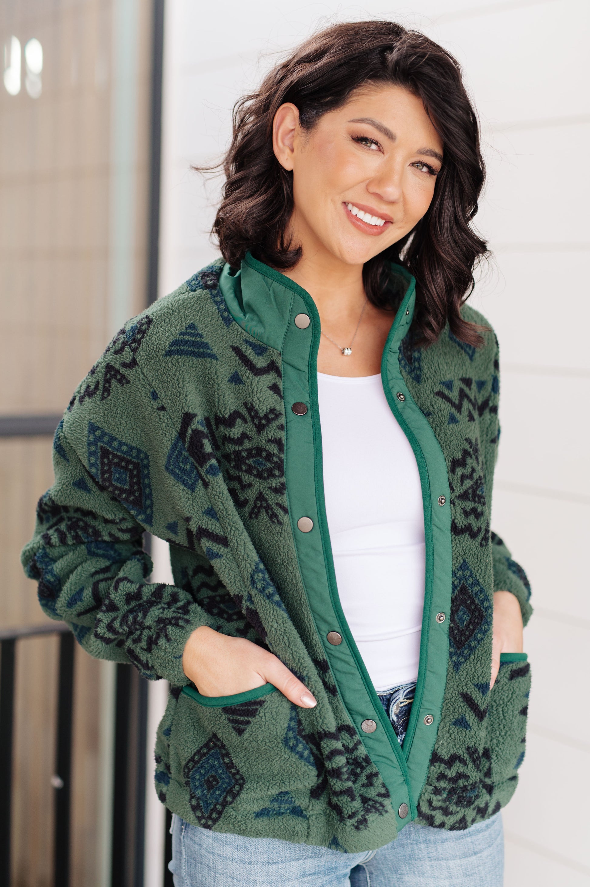 Woman wearing a green patterned cardigan with a plain background