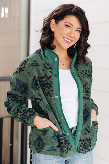 Woman wearing a green patterned cardigan with a plain background
