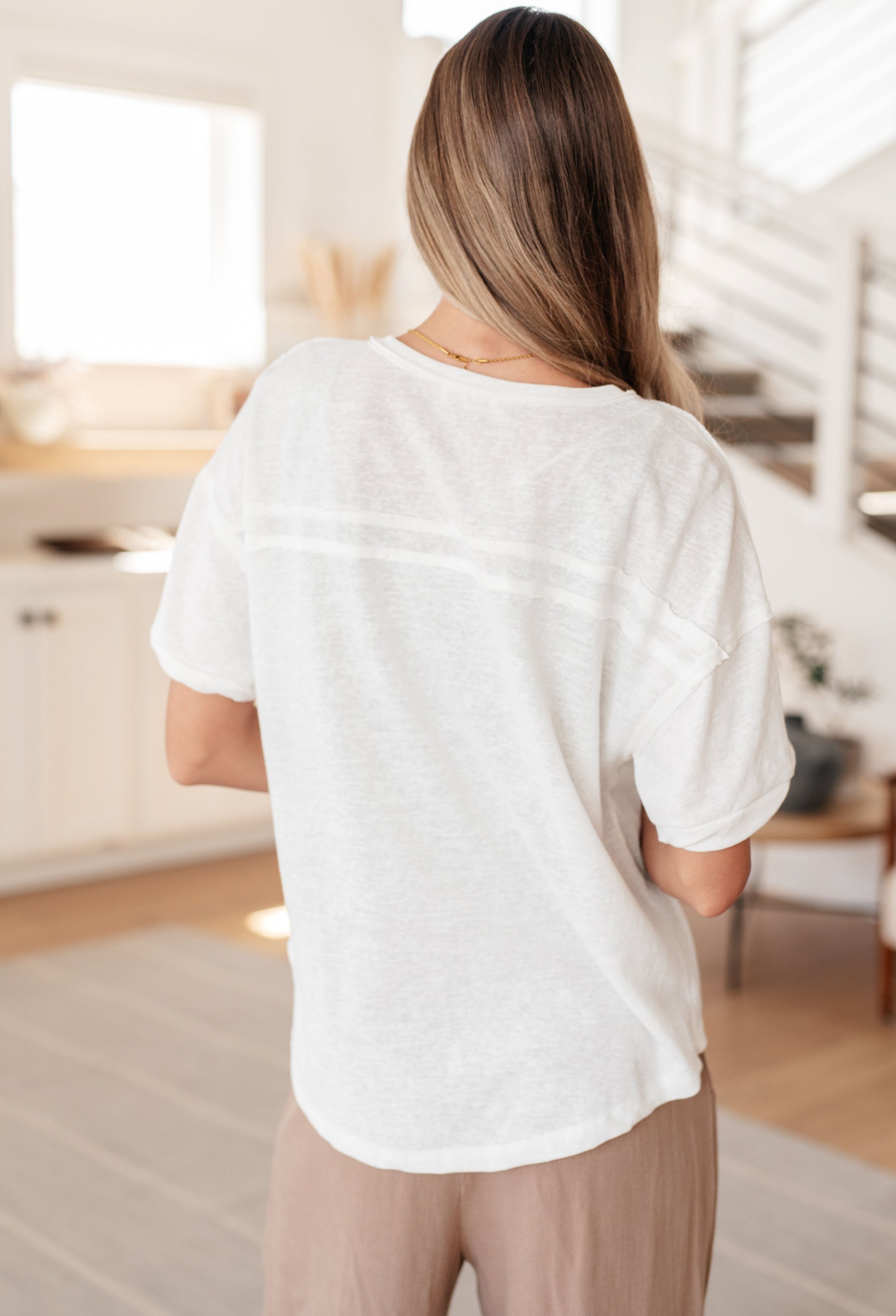 Person wearing a white t-shirt in a bright room with neutral decor